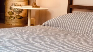 A bed with striped bedding, a bedside lamp, a small table, and a decorative item on the wall. - Zelda's House - 500 meters from the center (Cremona)
