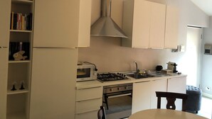 A modern kitchen with white cabinetry, a gas stove, a microwave, and a built-in oven. - Zelda's House - 500 meters from the center (Cremona)