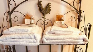 A metal rack with four towel stacks, each with a bottle of lotion and a wooden comb. - Zelda's House - 500 meters from the center (Cremona)