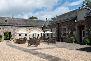 A stone building with outdoor seating and umbrellas.