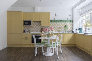 A kitchen with yellow cabinets, a microwave, a sink, and a dining area with a table and chairs.