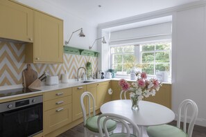 A kitchen with yellow cabinets, a white countertop, and a window with a view of greenery.