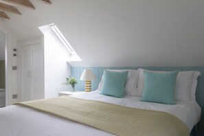 A bedroom with a bed, a nightstand, a lamp, and a window.