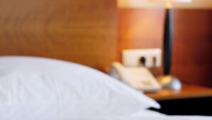 Una habitación de hotel con una cama, una mesita de noche y una lámpara.