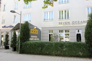 Un hotel con un letrero que dice 'Hansa Part-Hotel' y un restaurante de mariscos llamado 'Seven Oceans Seafood Restaurant' cerca.