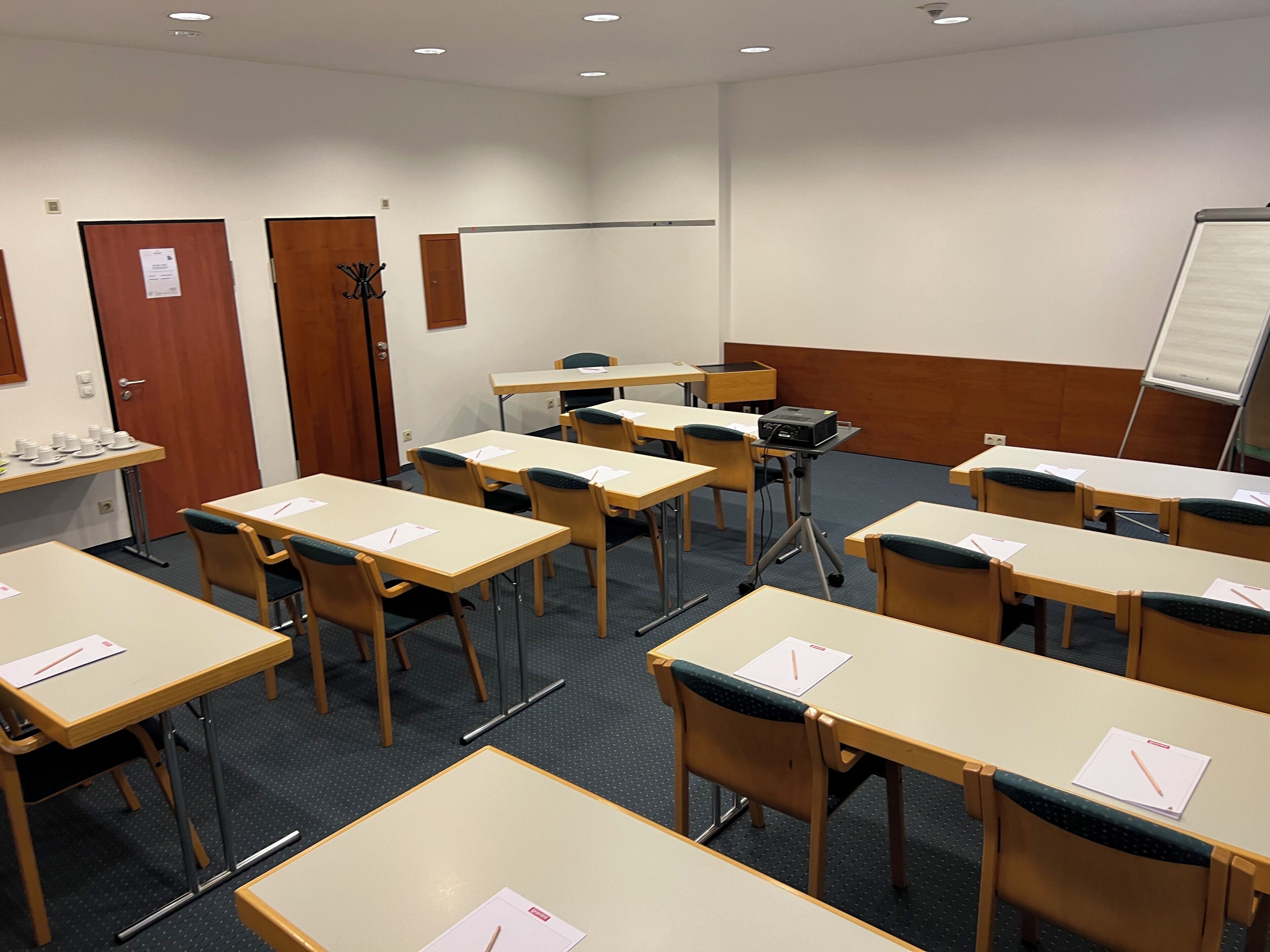 A conference room with multiple tables and chairs, a whiteboard, and a projector.