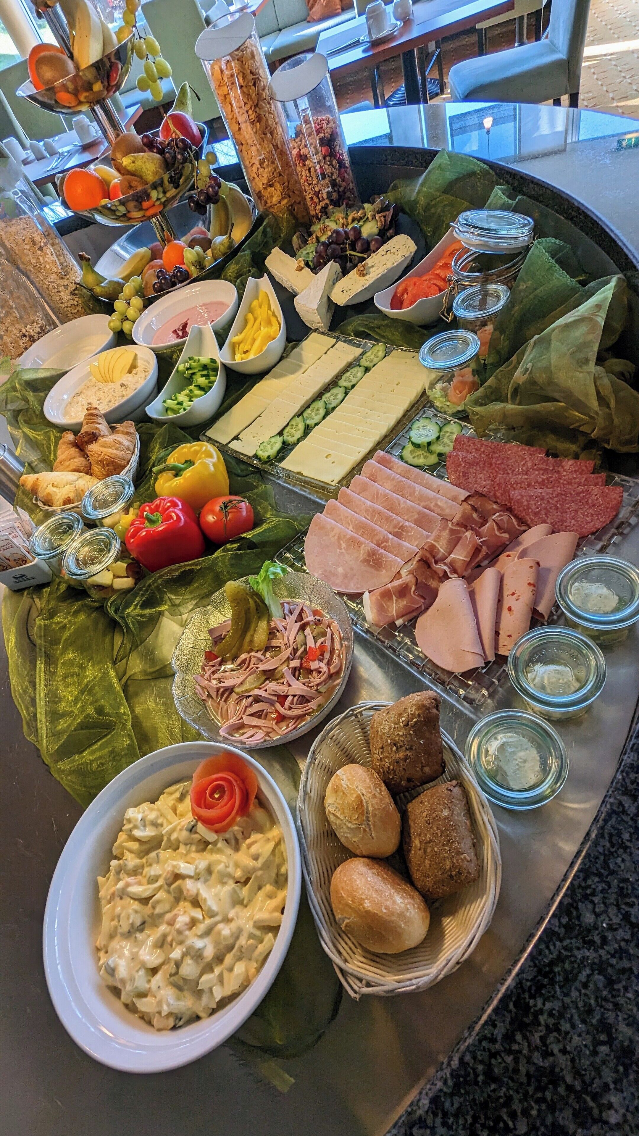 Monipuolinen buffetpöytä, jossa on tarjolla erilaisia ruokia, kuten lihaa, juustoja, hedelmiä ja vihanneksia.