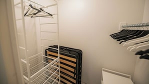 Vestidor con espacio para colgar y estantes, que contiene ropa doblada ordenadamente y una maleta.