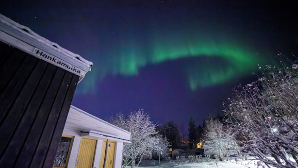 Edificio cubierto de nieve con un letrero que dice "Hankamuika" y vistas de las auroras boreales.