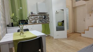 A compact living space with a kitchenette, a dining area, and a staircase. - Trastevere Cottage (Roma)