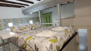 A bedroom with a bed, a bedside table, a mirror, and a green curtain. - Trastevere Cottage (Roma)
