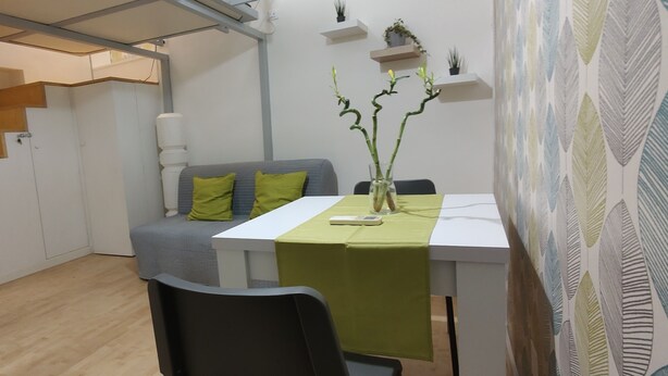 A modern living space with a staircase, a dining area with a table and chairs, and a sofa with cushions. - Trastevere Cottage (Roma)