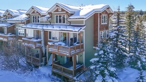 A multi-story residential building with balconies and a snow-covered landscape.