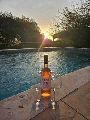 Una botella de vino rosado Simpli O. Jose y dos copas junto a una piscina.