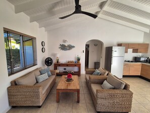 A modern living room with wicker furniture, a wooden coffee table, and a ceiling fan.