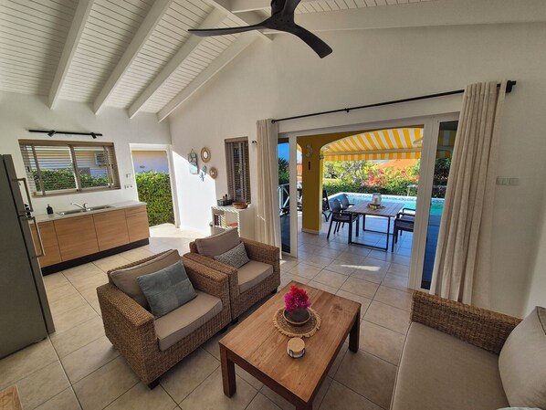 A modern living area with a kitchen, dining space, and a view of a pool. - Villa Karawara with private pool and lovely peaceful garden! (Bandabao)