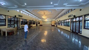 A spacious hall with a polished floor, large windows, and a chandelier.