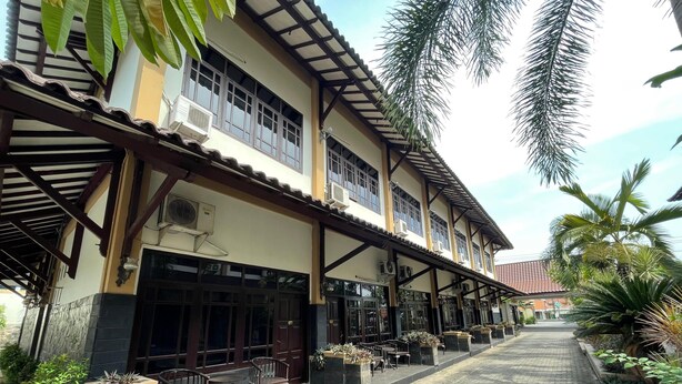 A two-story building with a covered patio area, outdoor seating, and potted plants.