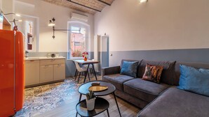 Ein modernes Wohnzimmer mit grauem Sofa, einem kleinen Couchtisch und einem Essbereich mit Tisch und Stühlen.