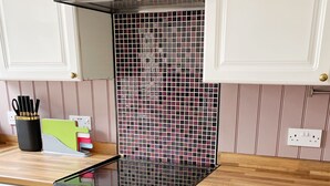 Eine Küche mit weißen Schränken, einer schwarzen Dunstabzugshaube und einer gefliesten Spritzschutzwand.