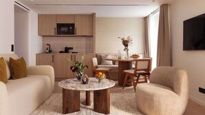 A modern living room with a sofa, a round coffee table, and a dining area with a table and chairs.