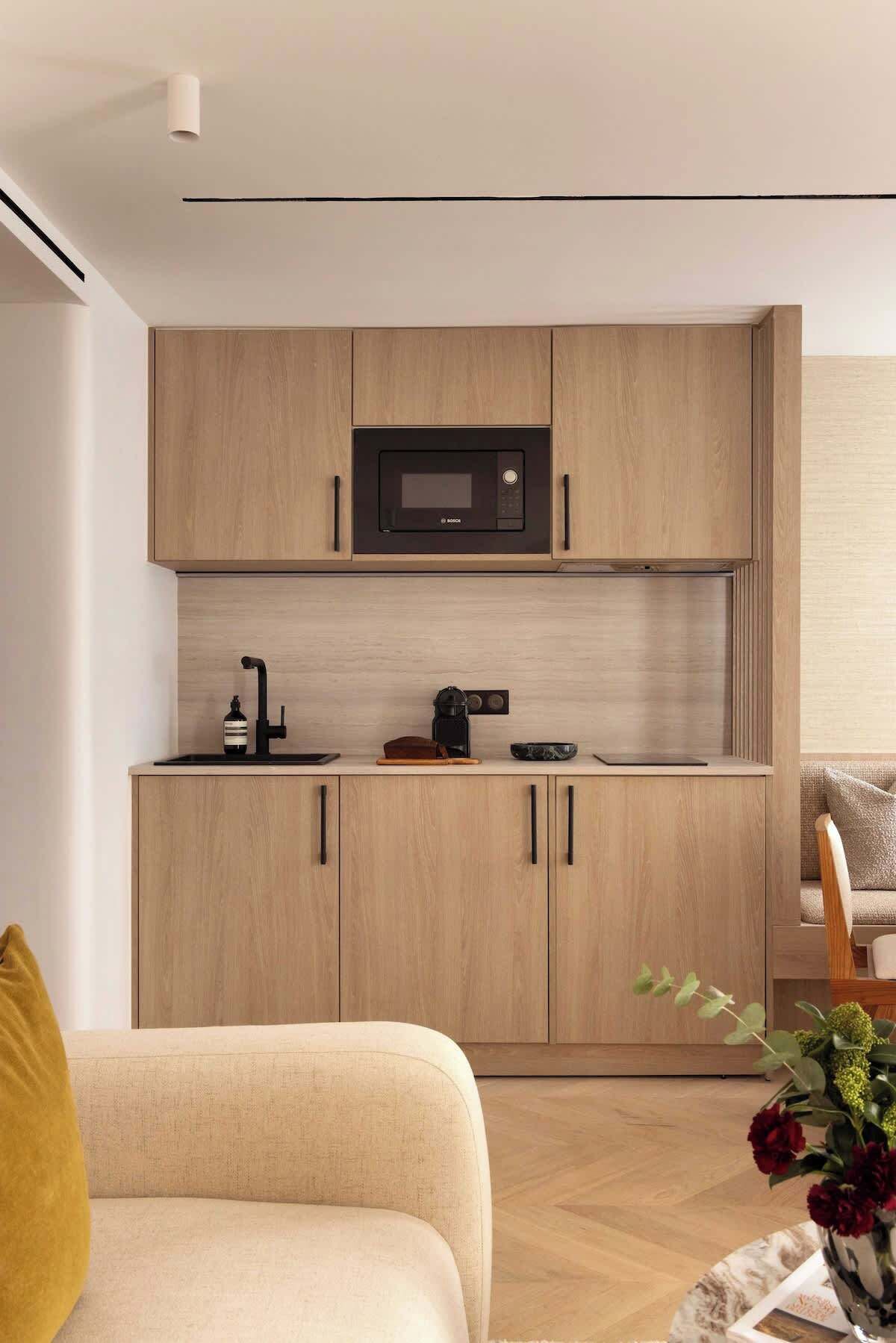 Een moderne keuken met houten kastjes, een inbouwmagnetron, een koffieapparaat en een spoelbak.