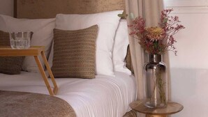 A bedroom with a bed, pillows, a bedside table with a vase, and a window with curtains. - Charming modern Studio with AC - Le Marais (Paris)
