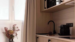A modern kitchen with wooden cabinets, a black microwave, and a coffee machine. - Charming modern Studio with AC - Le Marais (Paris)
