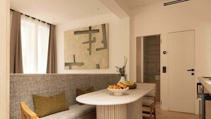 A modern living room with a grey sofa, a round table with a bowl of pastries, and a large abstract painting on the wall.