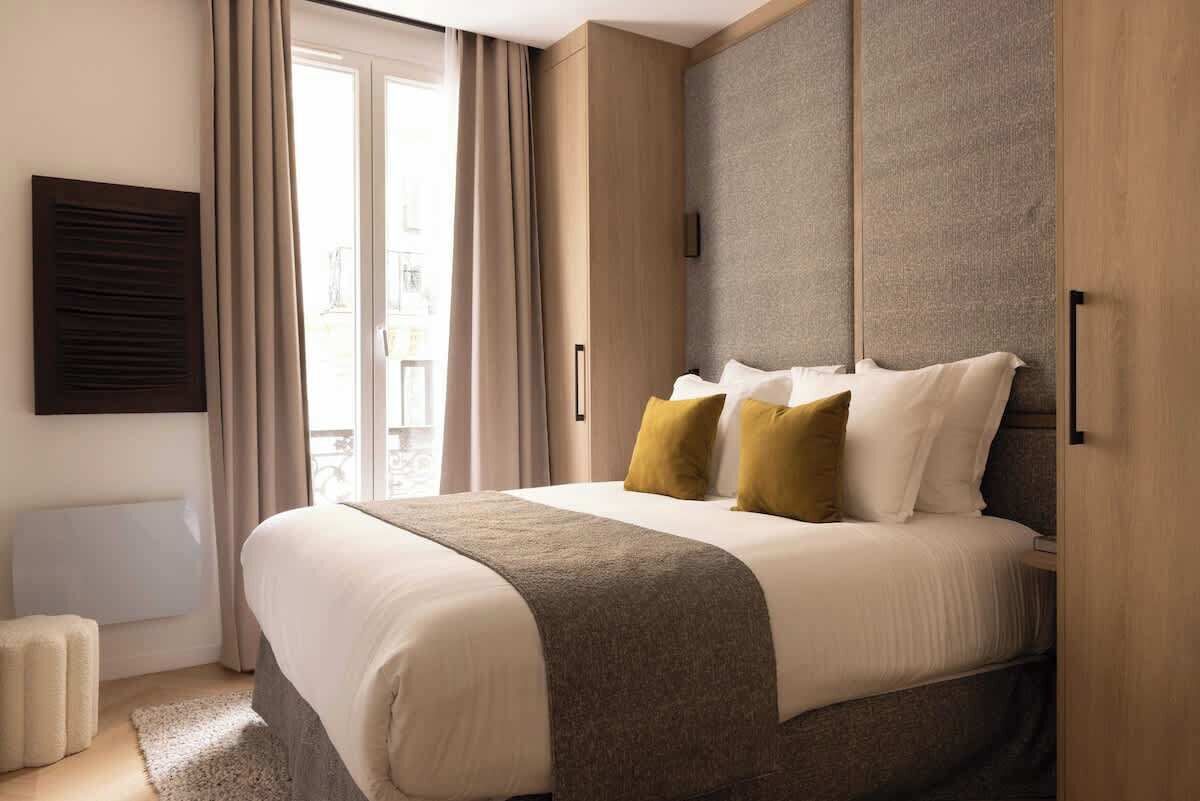 Et moderne hotelværelse med en stor seng, udsigt til byen gennem vinduet og et indbygget skab.