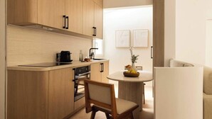 A modern kitchen with wooden cabinets, a built-in oven, a coffee maker, and a dining area with a round table and chairs.