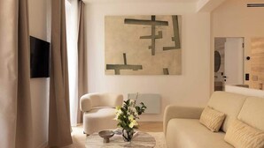 A modern living room with a beige sofa, a round coffee table, and a minimalist abstract painting on the wall.