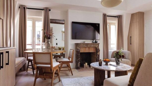 A modern living room with a fireplace, a dining area, and a TV mounted on the wall. - Charming flat - AC - 2BR-6P- le Marais (Paris)