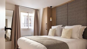 A modern hotel room with a large bed, a wooden headboard, and a view of the outdoors through a window. - Charming flat - AC - 2BR-6P- le Marais (Paris)
