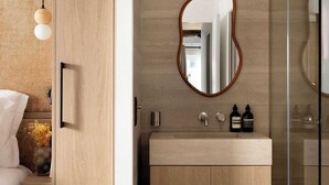 A modern bathroom with a wooden vanity, a round mirror, and a glass shower enclosure. - Charming flat - AC - 2BR-6P- le Marais (Paris)