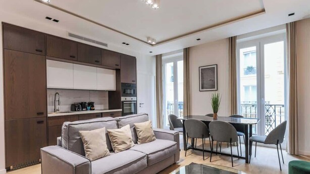 A modern living room with a grey sofa, a glass coffee table, and a dining area with a table and chairs. - Superb AC Apartment Center of Paris (Paris)