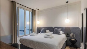 A modern hotel room with a large bed, two bedside tables, a window with curtains, and two pendant lights. - Superb AC Apartment Center of Paris (Paris)