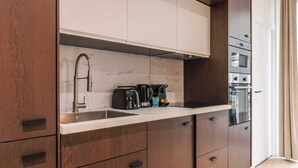 A modern kitchen with a marble backsplash, stainless steel appliances, and wooden cabinetry. - Superb AC Apartment Center of Paris (Paris)