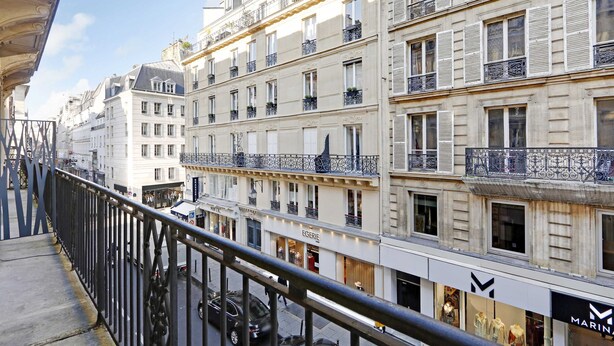 Un edifici de diverses plantes amb balcons, botigues i una passera per a vianants.