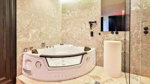 A modern bathroom with a freestanding bathtub, a large mirror, and a marble wall.