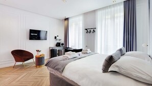 Habitación de hotel moderna con una cama grande, un televisor de pantalla plana, un escritorio con ordenador y una silla.