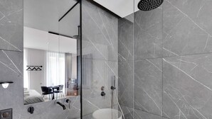 Un baño moderno con un espejo grande, una bañera y una ducha.