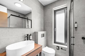 A modern bathroom with a large white sink, a mirror, a toilet, and a shower area. - Luxurious Apartment with Jacuzzi, Sea View, and Balcony in Istria (Brtonigla)