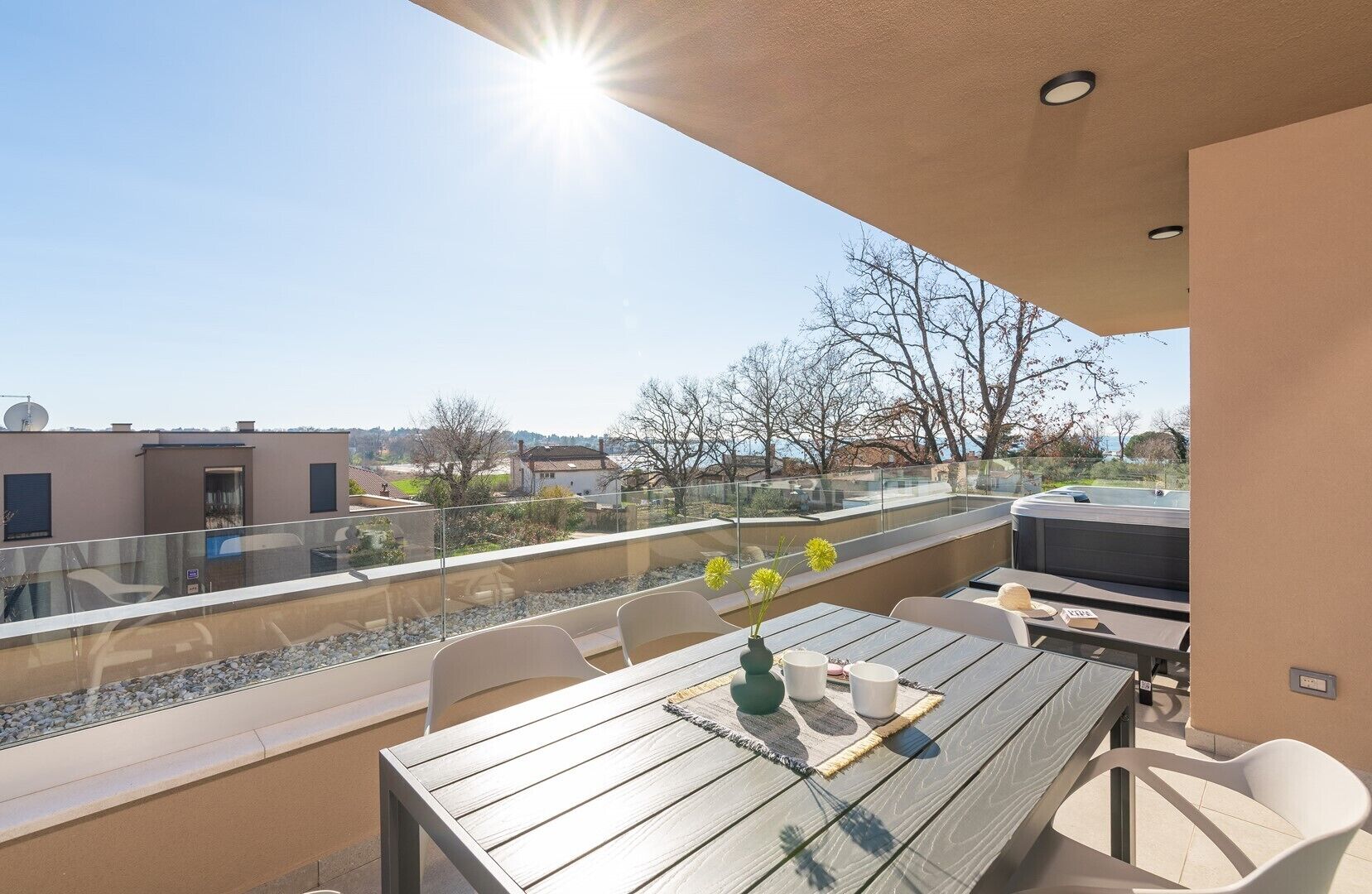 Eine Dachterrasse mit Holztisch, Stühlen und einem Grill.