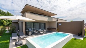 A modern house with a swimming pool, outdoor seating, and a barbecue area. - Exclusive Ground-Floor Apartment with Private Pool and Terrace in Istria (Brtonigla)
