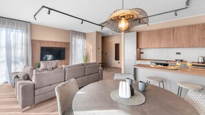 A modern living room with a sectional sofa, a dining table with chairs, and a kitchen area with wooden cabinets and a countertop. - Exclusive Ground-Floor Apartment with Private Pool and Terrace in Istria (Brtonigla)
