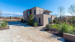 A modern two-story house with a paved driveway and landscaped garden. - Ground-Floor Apartment with Private Pool and Terrace in Istria, 150 Meters from the Sea (Brtonigla)