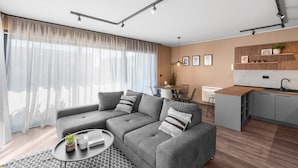 A modern living room with a grey sectional sofa, a round coffee table, and a dining area with a small table and chairs. - Ground-Floor Apartment with Private Pool and Terrace in Istria, 150 Meters from the Sea (Brtonigla)