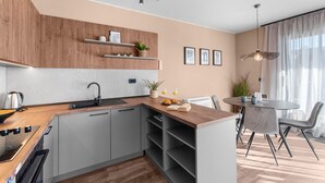 A modern kitchen with grey cabinets, a wooden countertop, and a dining area with a round table and chairs.