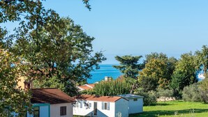 Blick auf die Küste mit einem kleinen weißen Gebäude, blauem Himmel und einem Schiff in der Ferne.